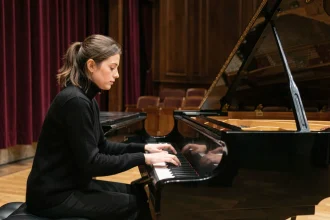 Jeune pianiste française concentrée lors d'une performance sur scène dans une salle de concert parisienne classique